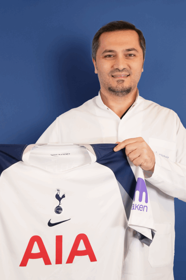 Bild zeigt, wie Dr. Abdulaziz Balwi ein Trikot des Premiere League Klubs Tottenham Hotspur in beiden Hände hält