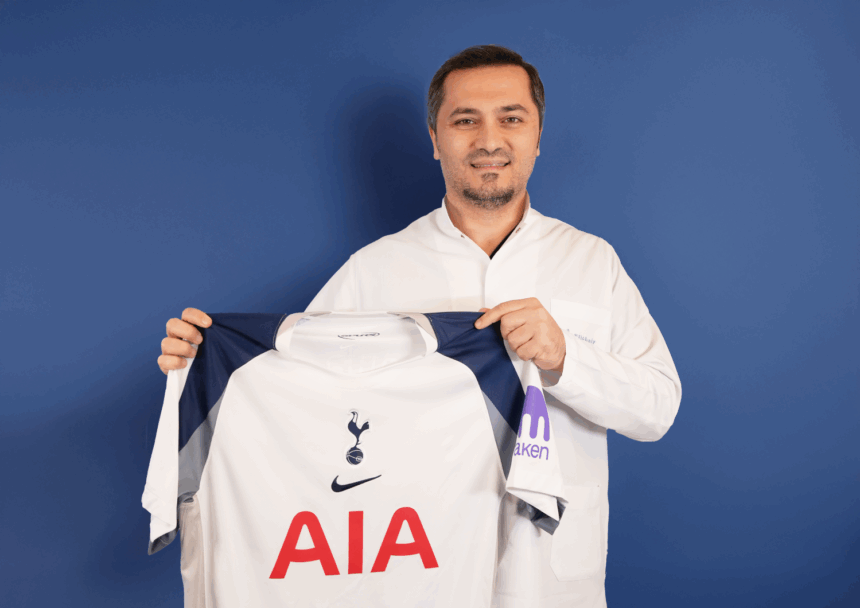Bild zeigt, wie Dr. Abdulaziz Balwi ein Trikot des Premiere League Klubs Tottenham Hotspur in beiden Hände hält